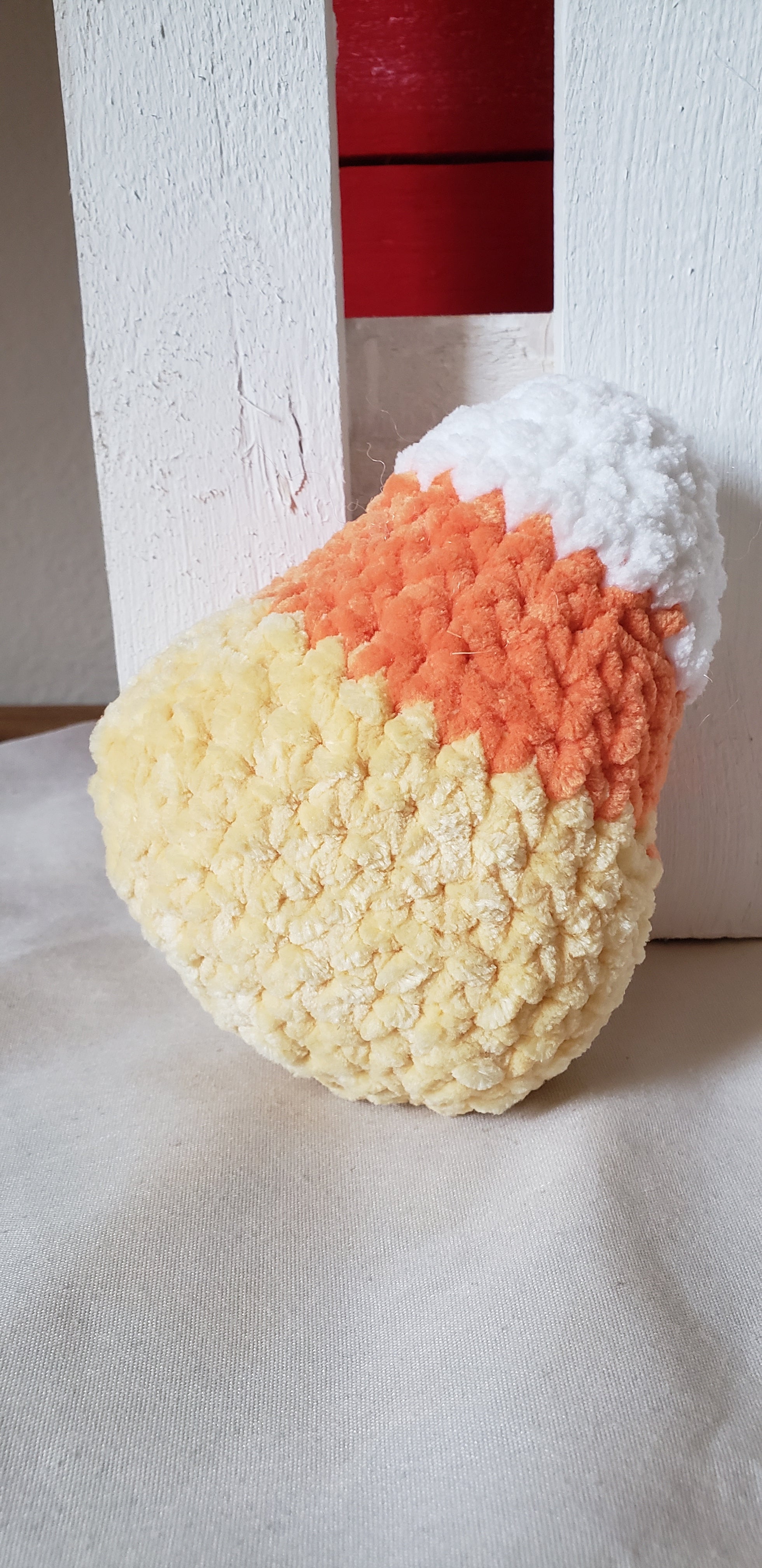 Crochet candy corn plushie side profile showing white, orange and yellow color bands