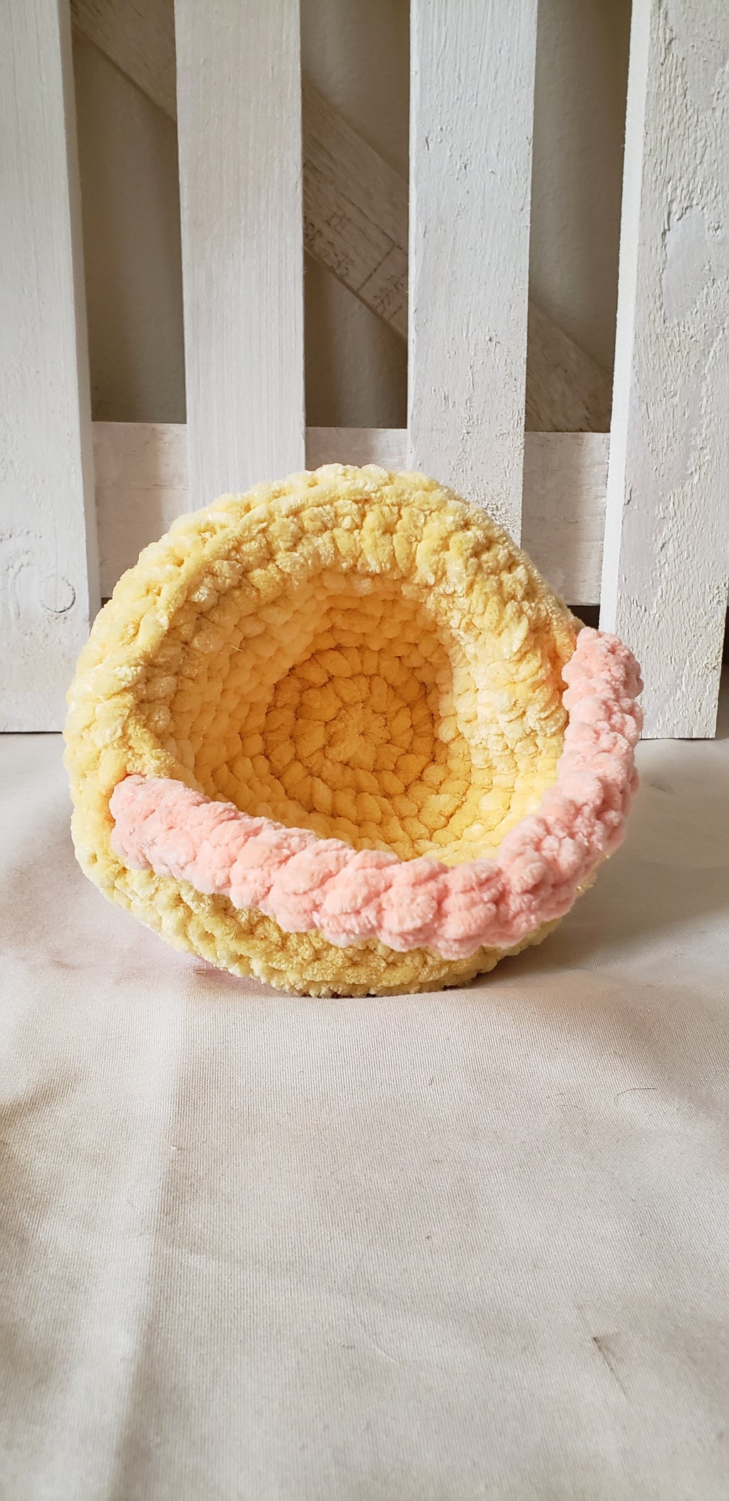 Small peach crochet Easter basket tipped on side showing yellow interior lining detail