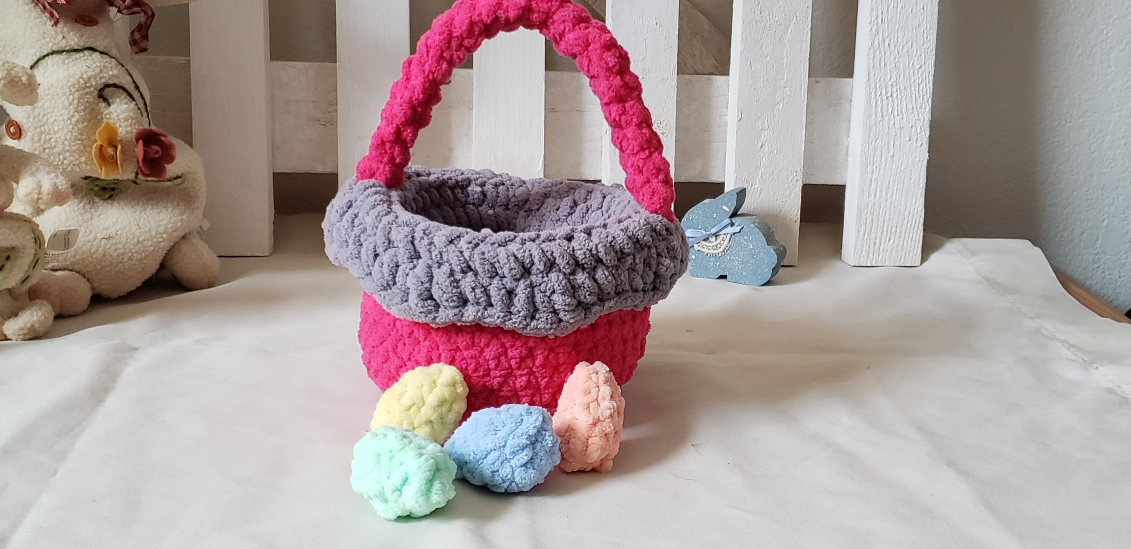 Hot pink crochet Easter basket with pastel eggs displayed with Easter bunny figurines - glamour shot