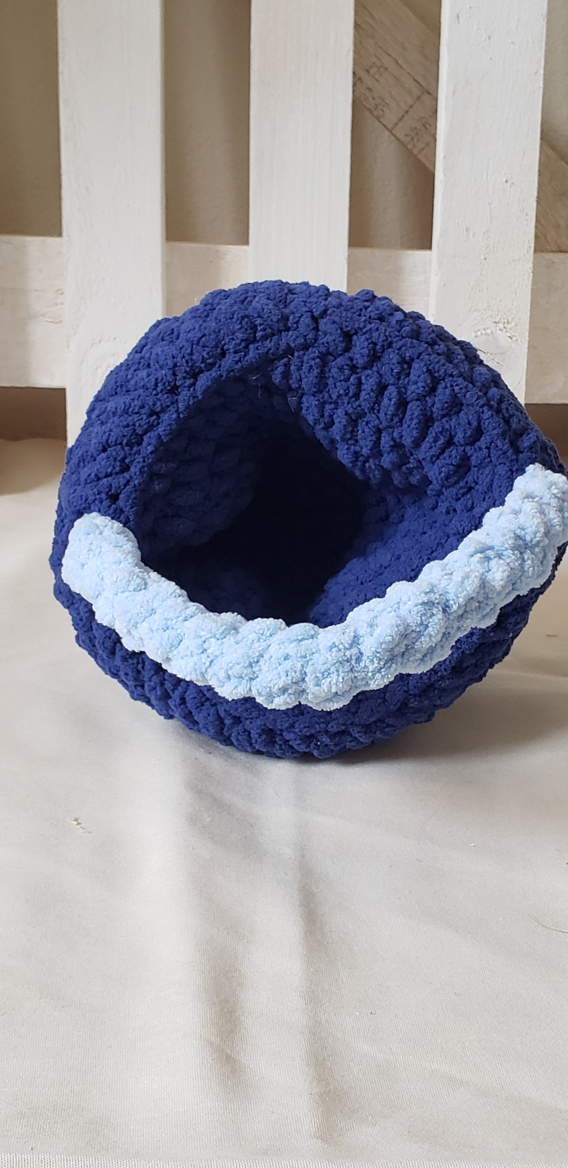 Two-tone blue crochet Easter basket side view with plush eggs displayed in front