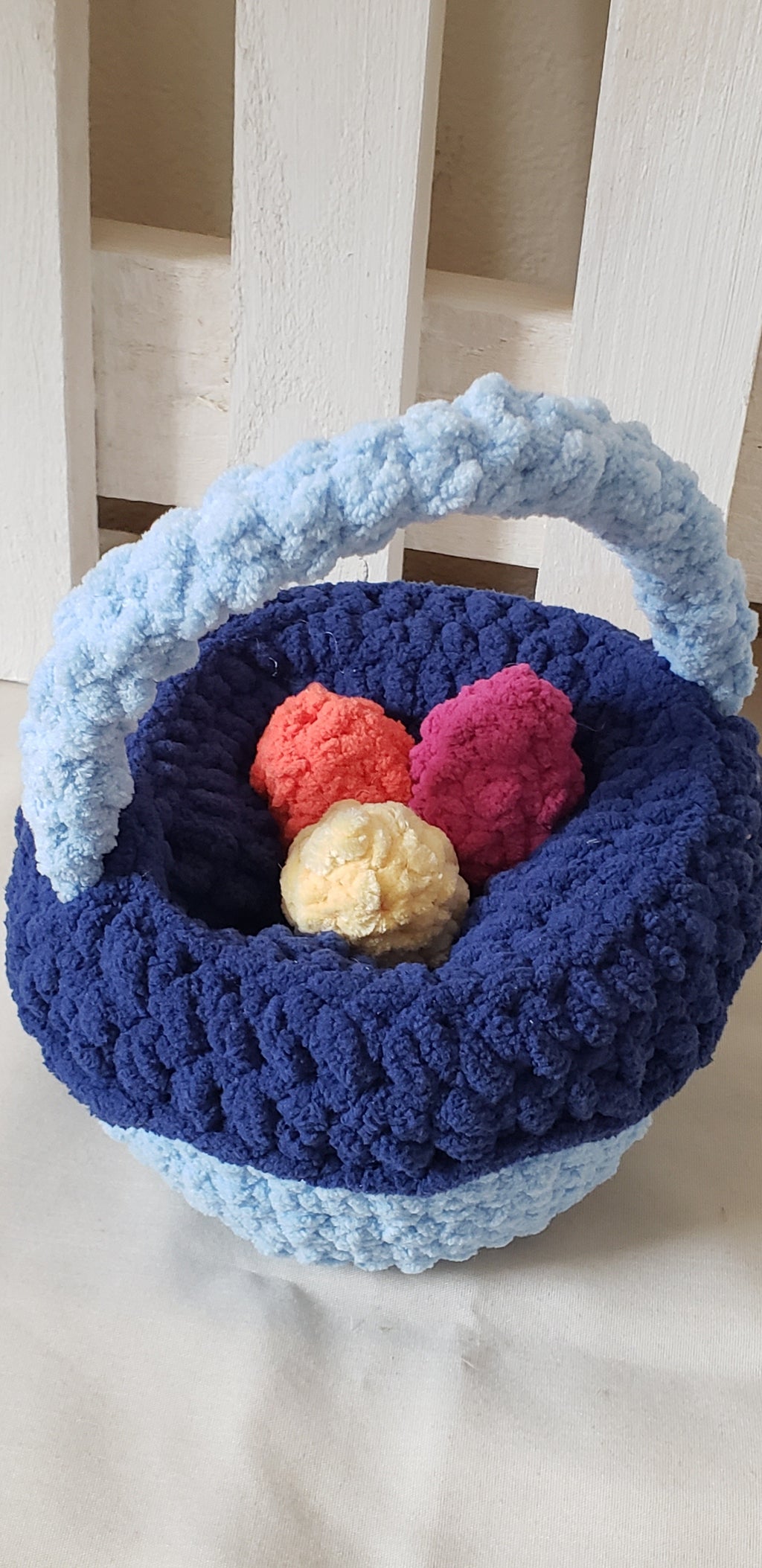 Two-tone blue crochet Easter basket with yellow, fuchsia and orange plush eggs inside