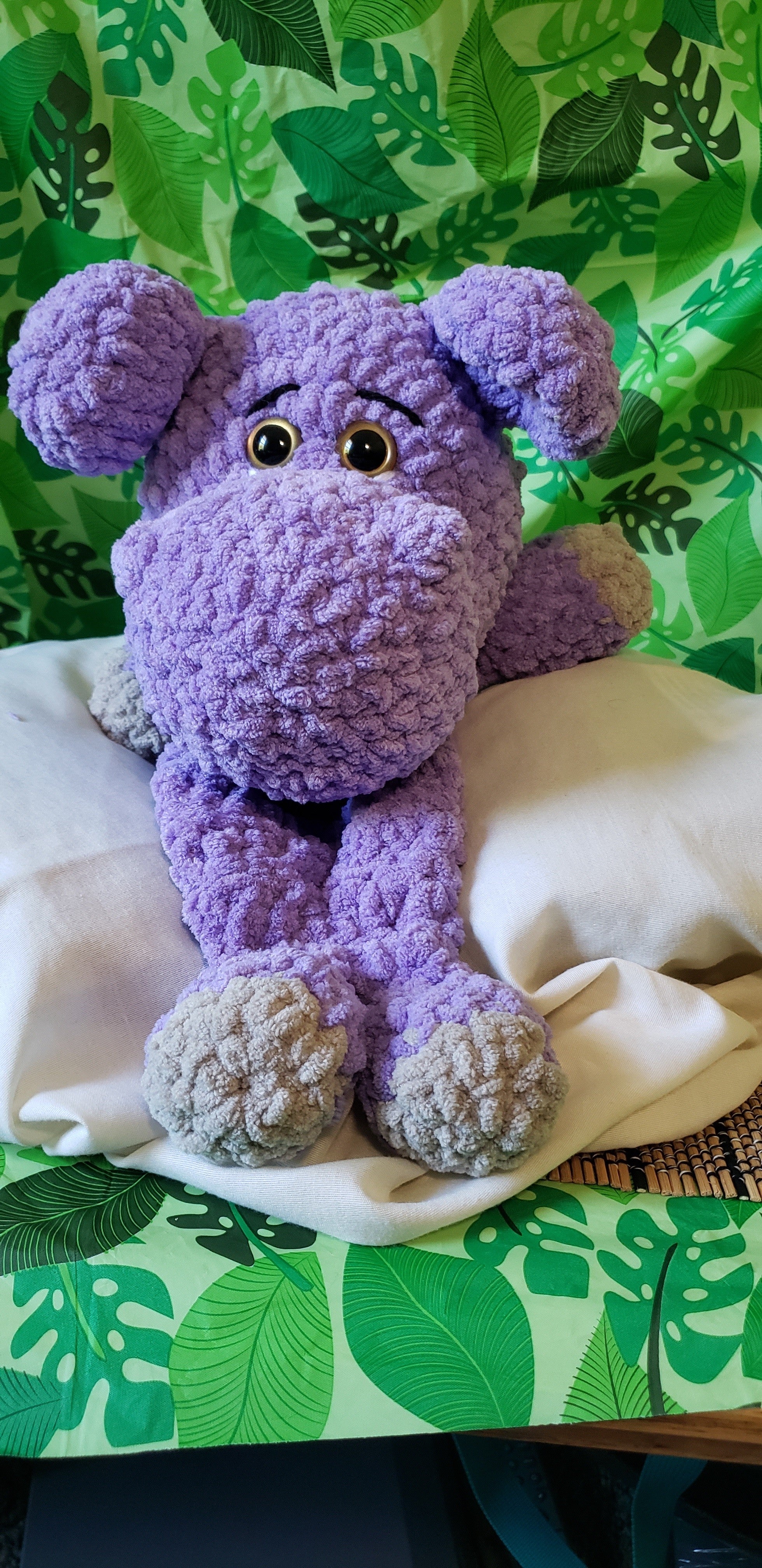 Front view of purple crocheted hippo snuggler with gray hands and feet
