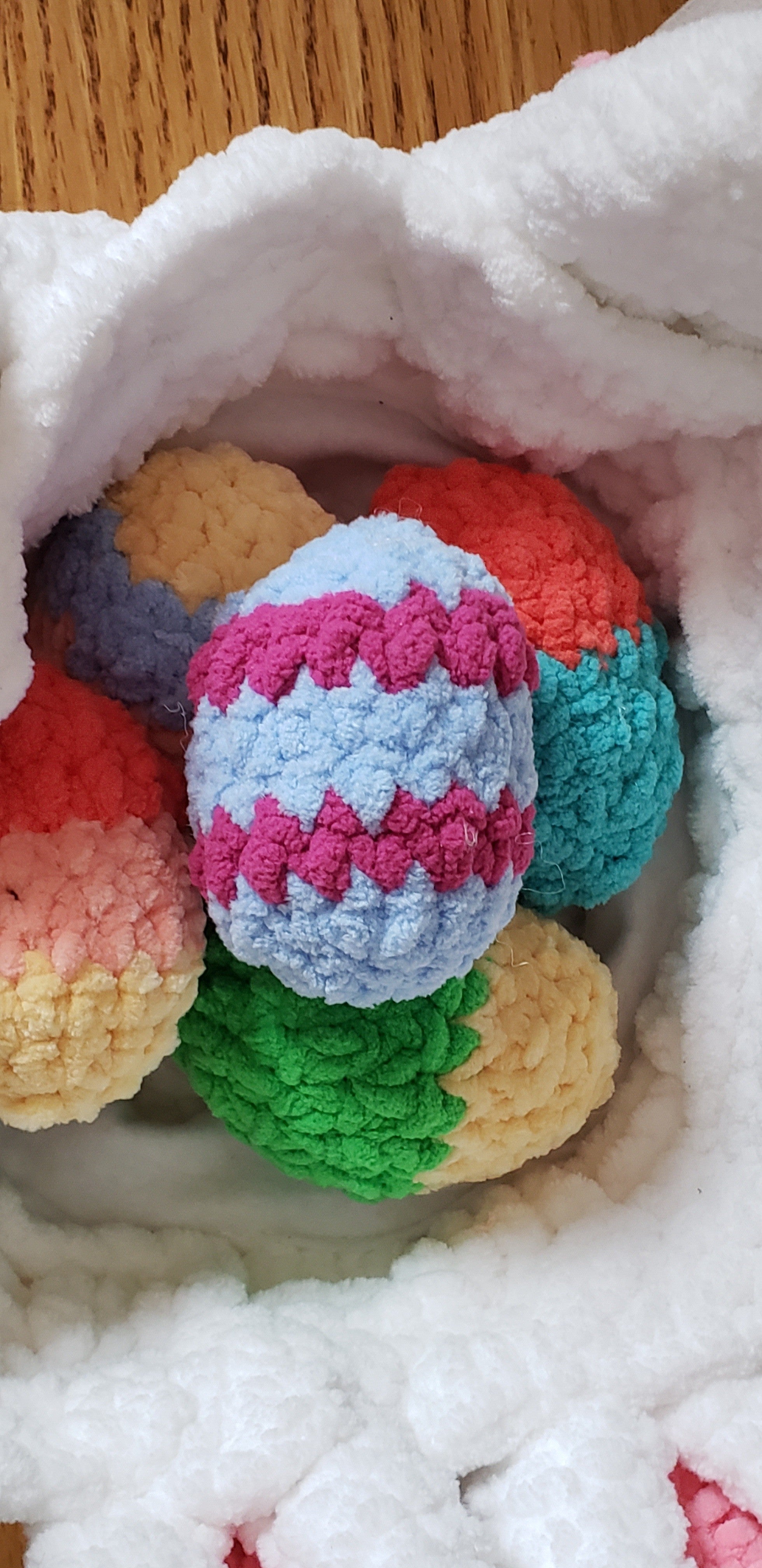 All 5 colorful crochet Easter eggs displayed inside the white bunny basket