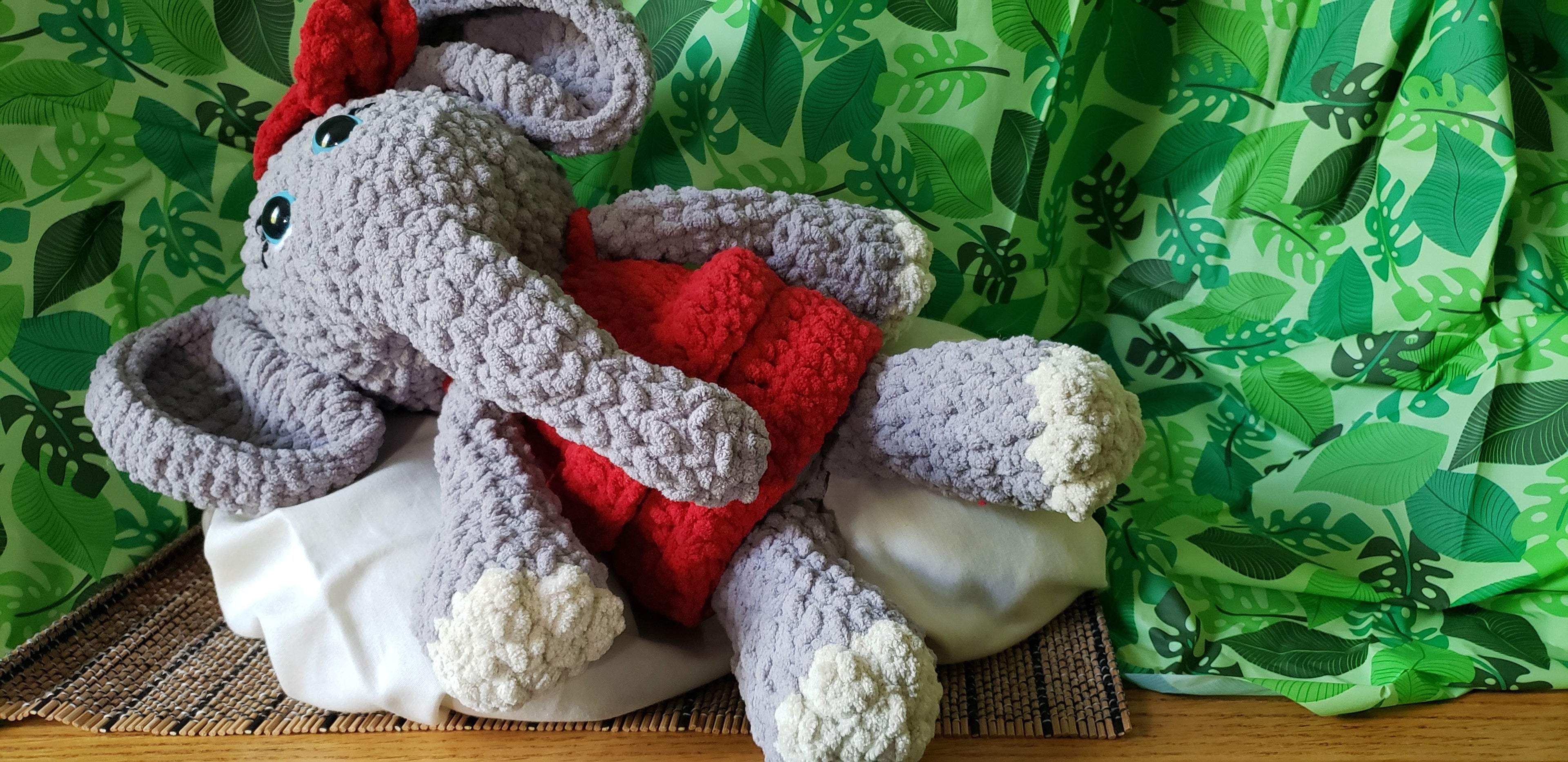 Crocheted elephant plushie laying down side view