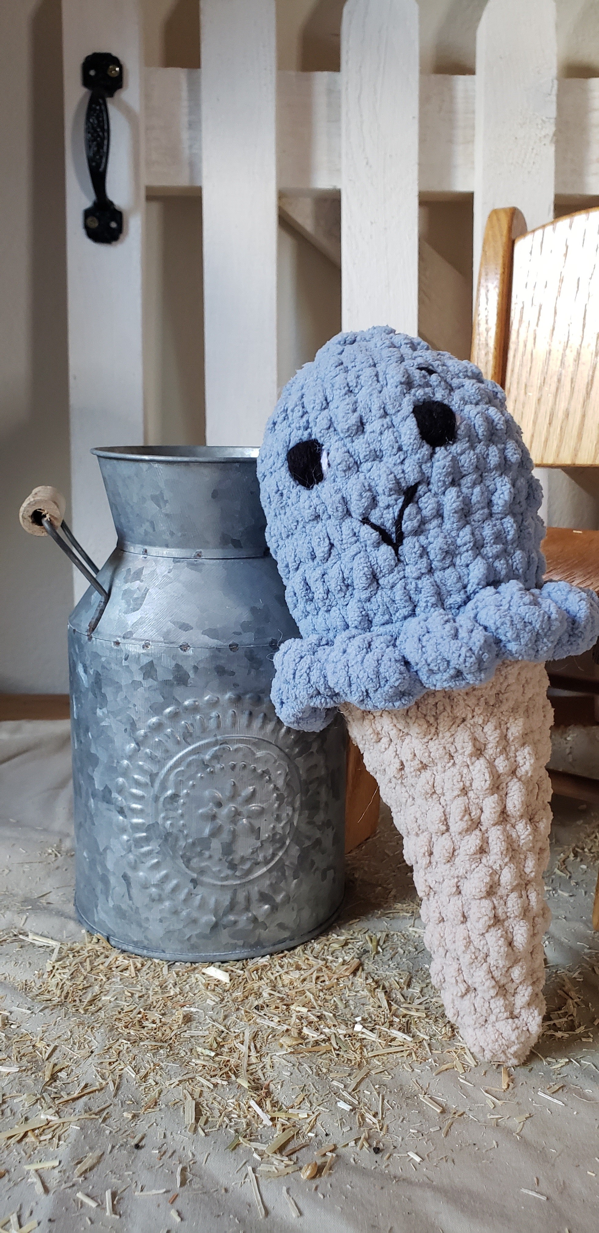 Crocheted blueberry ice cream plushie propped next to a galvanized milk can