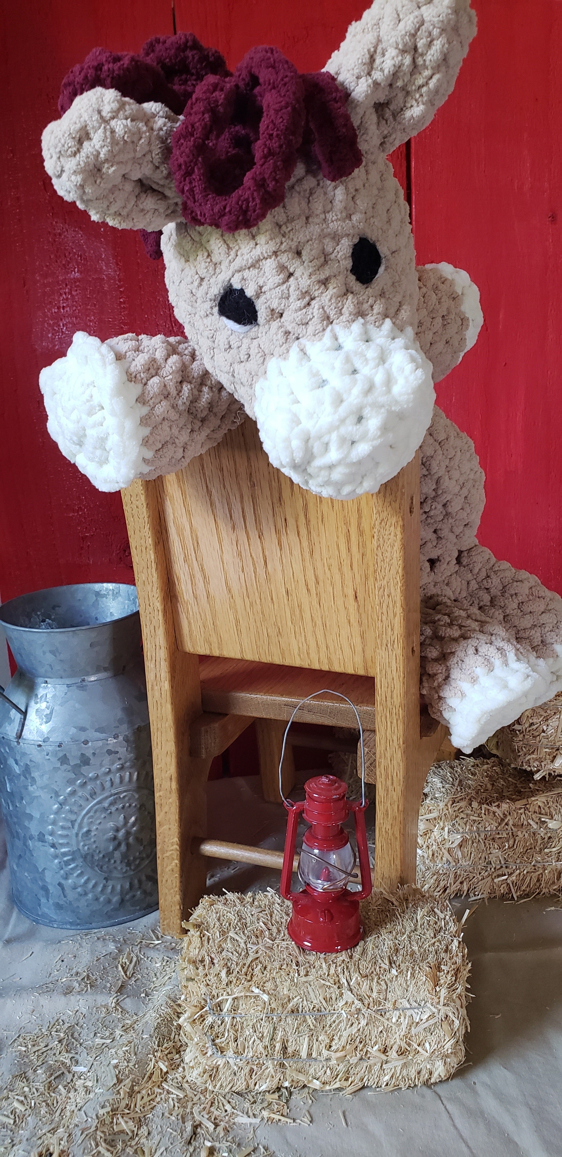 Side style shot of tan crocheted pony plushie peeking over wooden chair back
