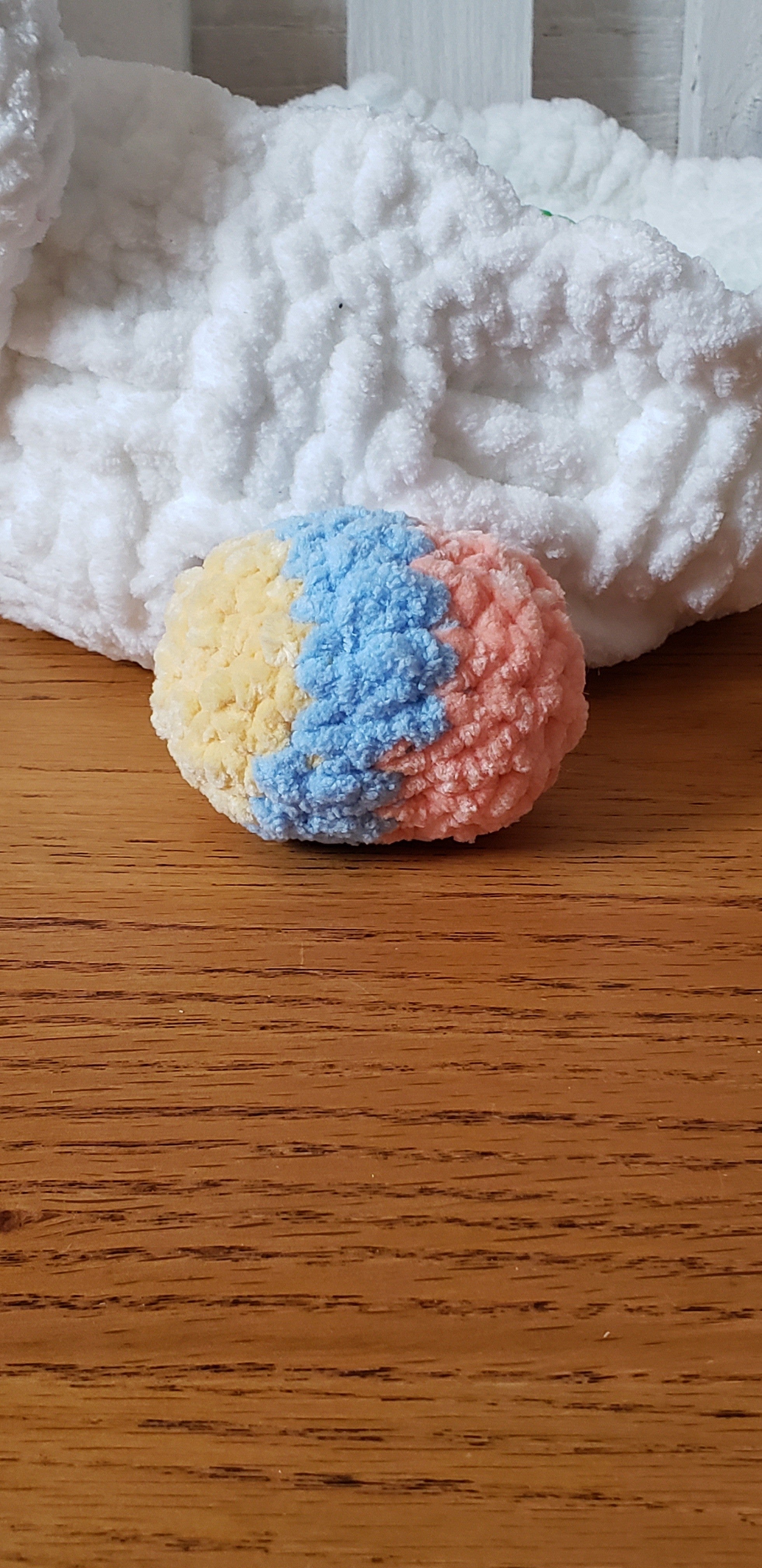 Pastel tri-color crochet Easter egg in blue, pink and yellow close-up