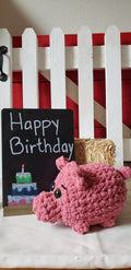 Pink crocheted mini pig plushie with Happy Birthday chalkboard sign