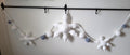 Crochet plush snowflake garland full length view showing 1 large center snowflake, 2 mini snowflakes and 8 plush balls in white and slate blue
