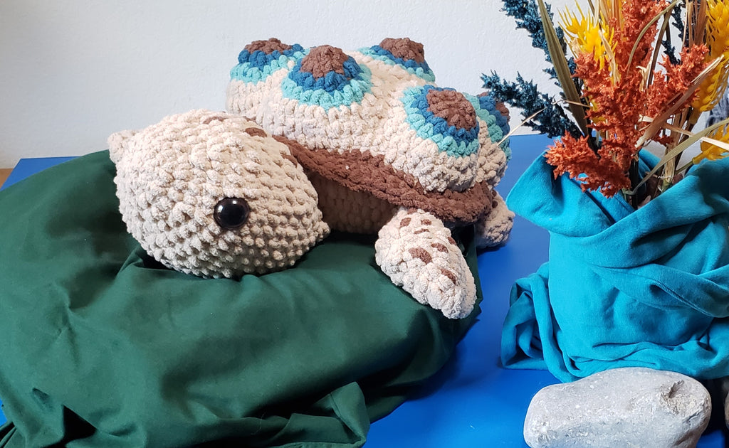 Crochet turtle plushie side view on green lily pad with coastal decor